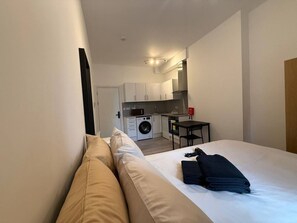 A hotel room with a bed, a small kitchenette, and a washing machine. - Modern Room | Minutes from Central London (Greater London)