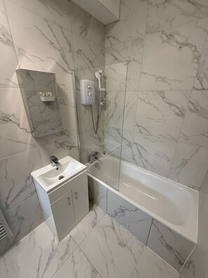 A bathroom with a bathtub, a sink, and a shower unit. - Modern Room | Minutes from Central London (Greater London)