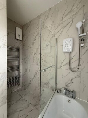 Ein modernes Badezimmer mit Duschkabine aus Glas, integriertem WC und einer Badewanne.
