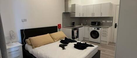 A modern bedroom with a bed, bedside table, and a small desk.