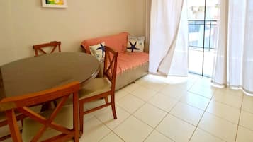 Un comedor con una mesa y sillas, un sofá con una manta y una ventana con cortinas.