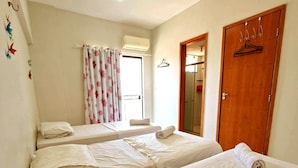 A room with two beds, a wooden door, and a window with curtains. - SaltBeach - Cobertura Ed.Atlantic Beach (Salinópolis)