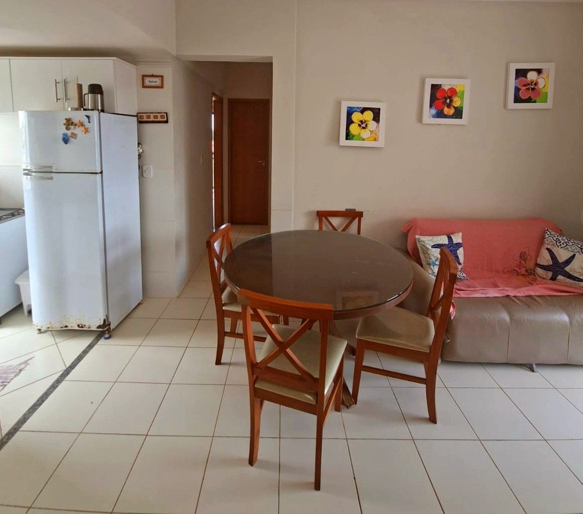 Un comedor con una mesa redonda y sillas de madera, un refrigerador blanco y un sofá con cojines.
