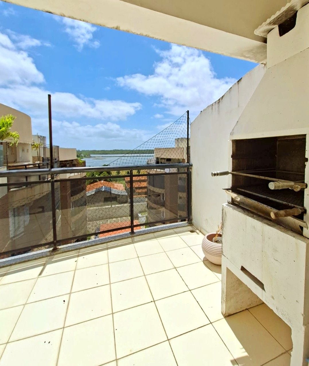 A balcony with a grill and a view of a bridge and water.