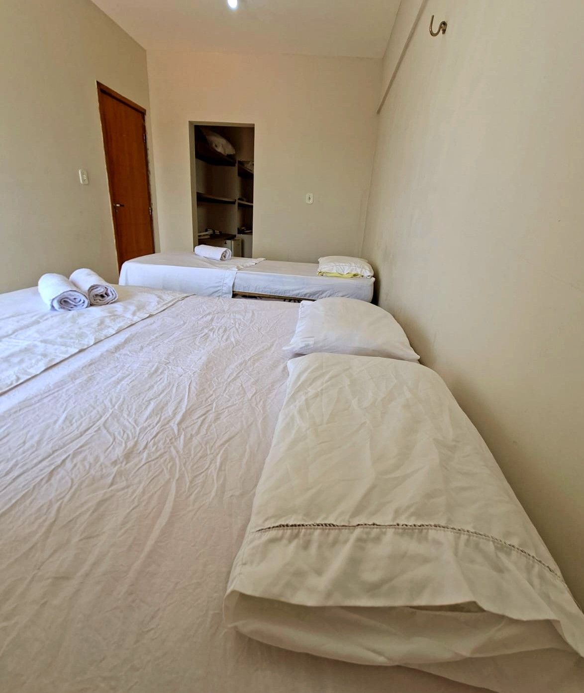 Habitación de hotel con dos camas, un armario y una puerta.