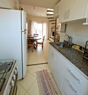 Una cocina con estufa, lavamanos y comedor.