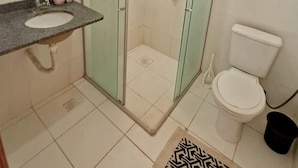 A bathroom with a glass-enclosed shower, a sink, a toilet, and a mirror. - SaltBeach - Cobertura Ed.Atlantic Beach (Salinópolis)