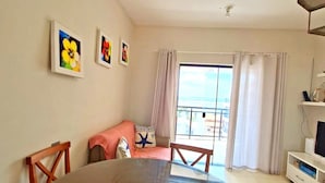 A room with a large round table, a sofa, a TV, and a balcony with curtains. - SaltBeach - Cobertura Ed.Atlantic Beach (Salinópolis)