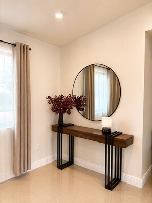 Un intérieur moderne avec une console en bois, un miroir et un vase orné de feuilles rouges.
