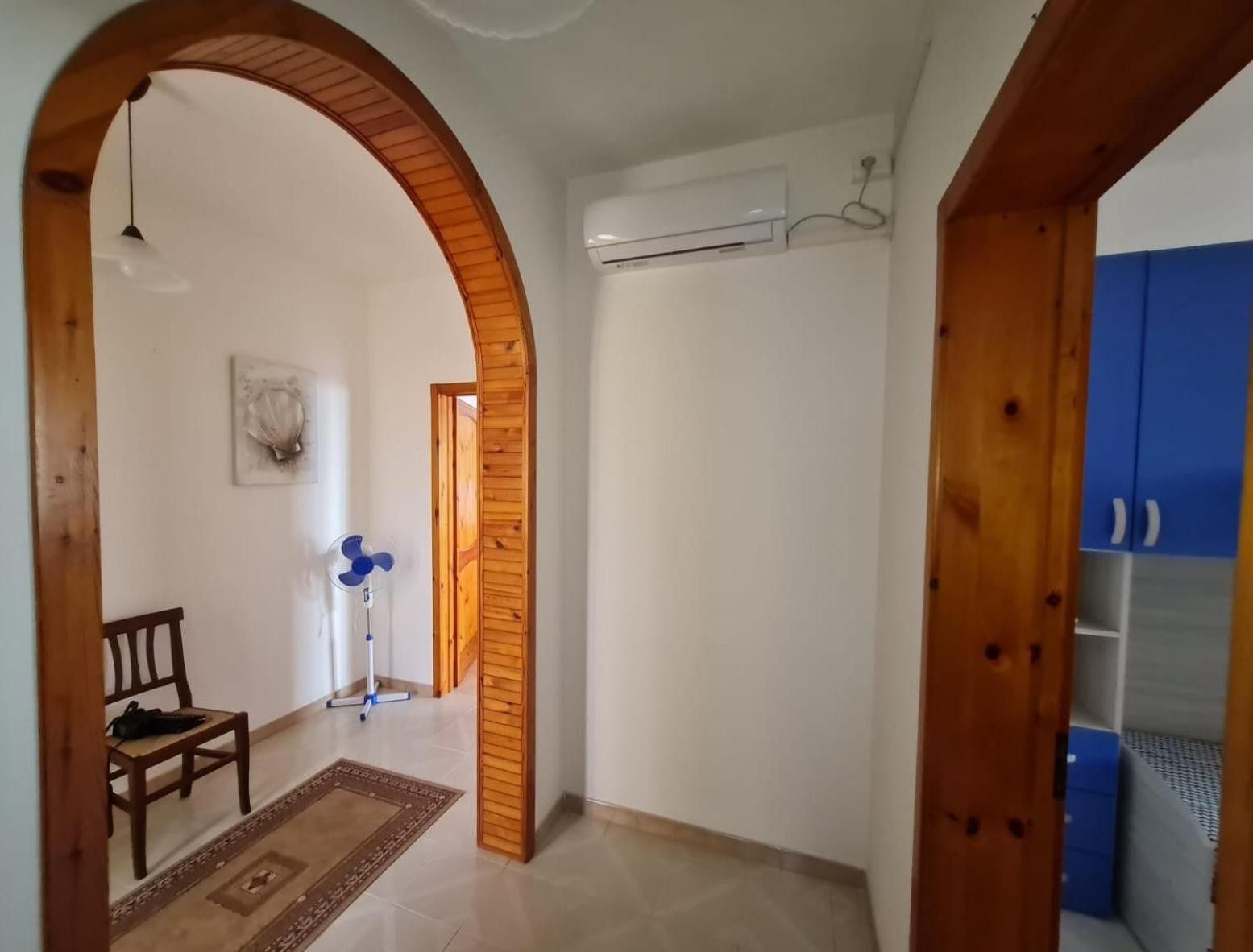 Un ambiente interno con un arco in legno, una ventola a soffitto, una sedia e un armadietto blu.