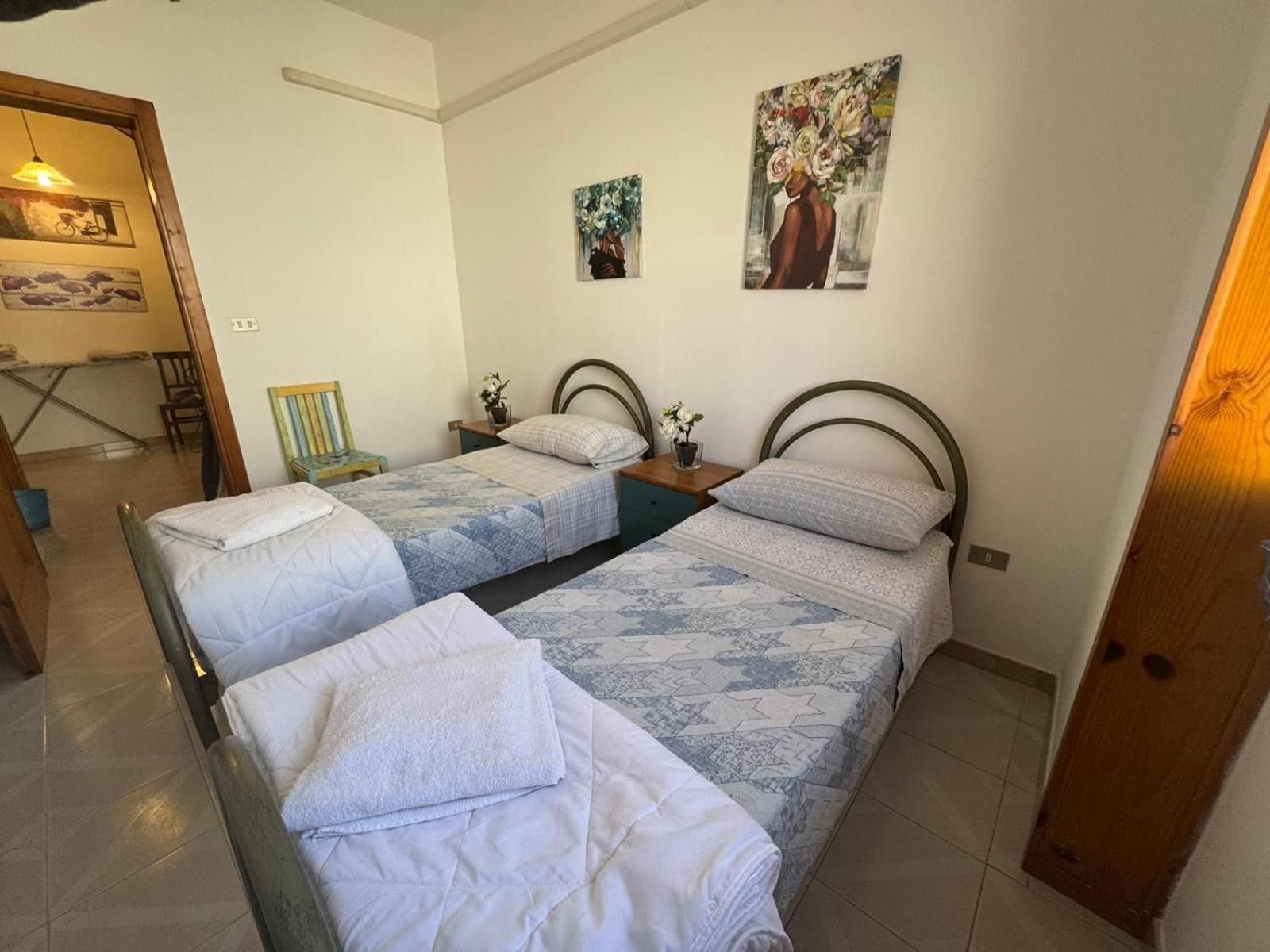 Een slaapkamer met twee eenpersoonsbedden, een tafeltje en een stoel.