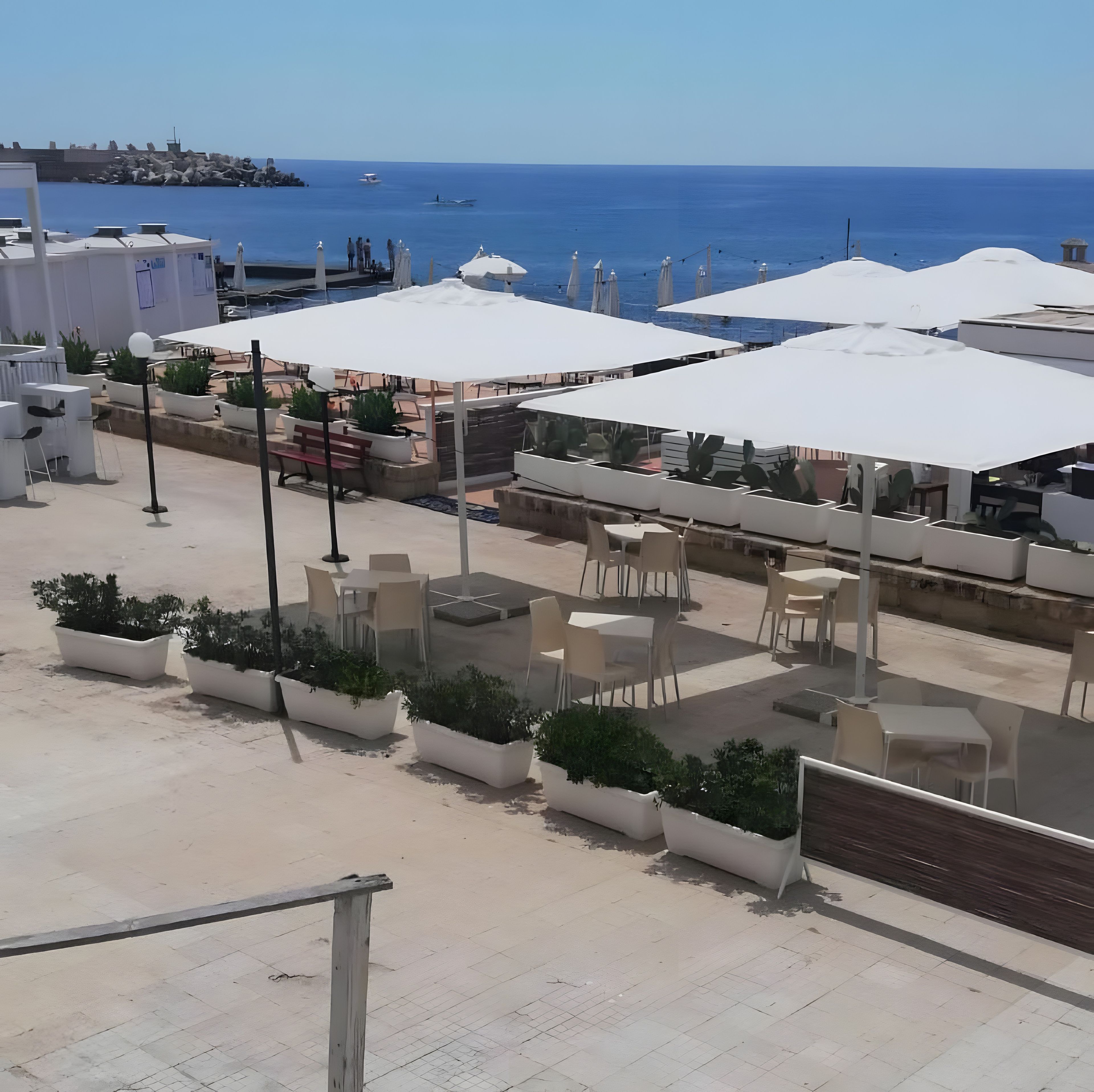 Un espace extérieur aménagé avec des tables, des chaises, des plantes en pot et des parasols.