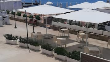Un espace extérieur aménagé avec des tables, des chaises, des plantes en pot et des parasols.