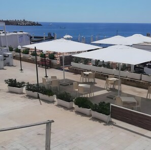 An outdoor seating area with tables and chairs, potted plants, and umbrellas. - Apartment 'Amata Villa Vacanza' with Private Garden, Wi-Fi and Air Conditioning (Santa Maria di Leuca)