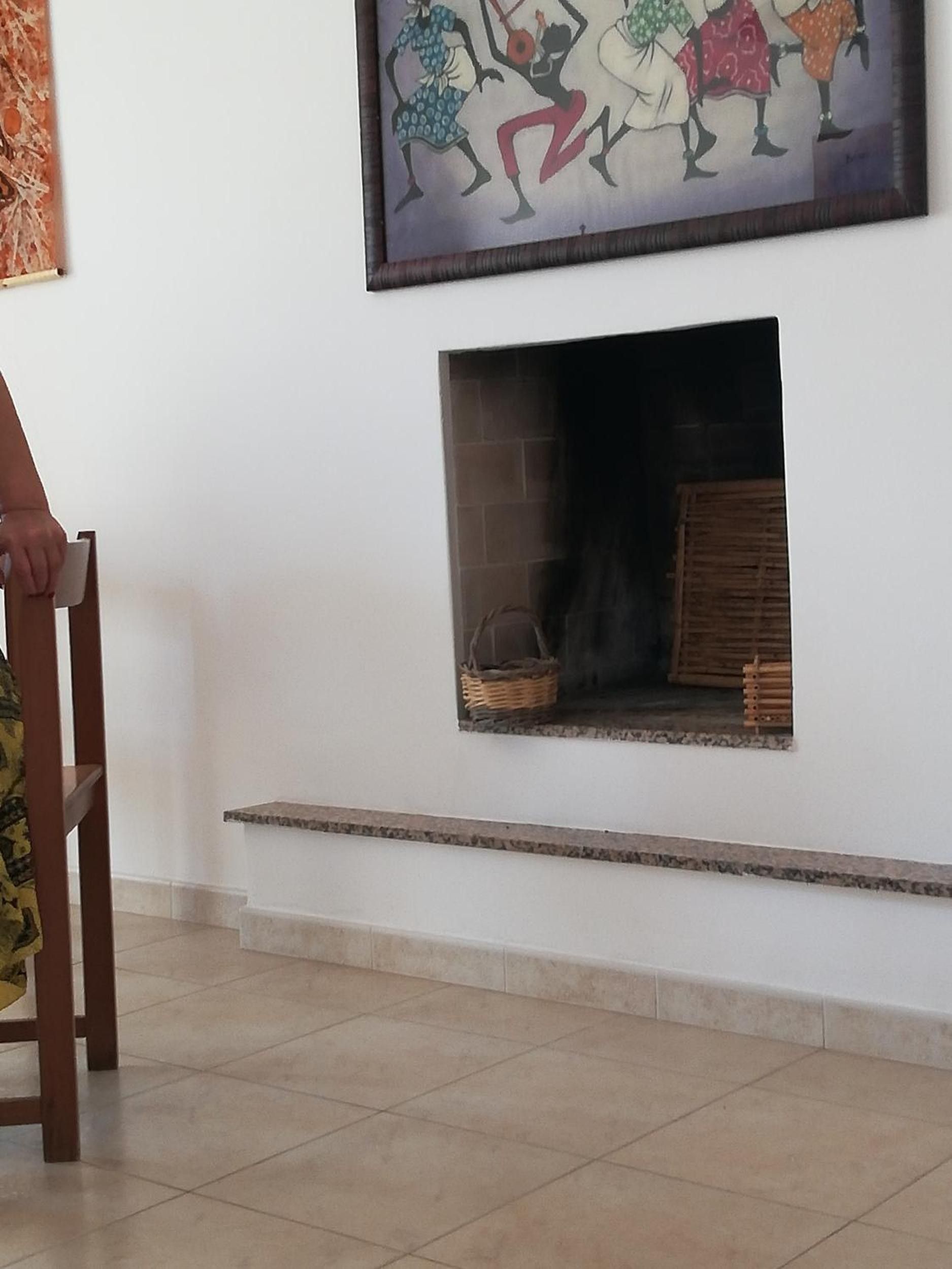 Una stanza con un camino, una poltrona e un quadro appeso al muro.