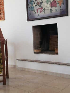 A room with a fireplace, a chair, and a painting on the wall. - Apartment 'Amata Villa Vacanza' with Private Garden, Wi-Fi and Air Conditioning (Santa Maria di Leuca)