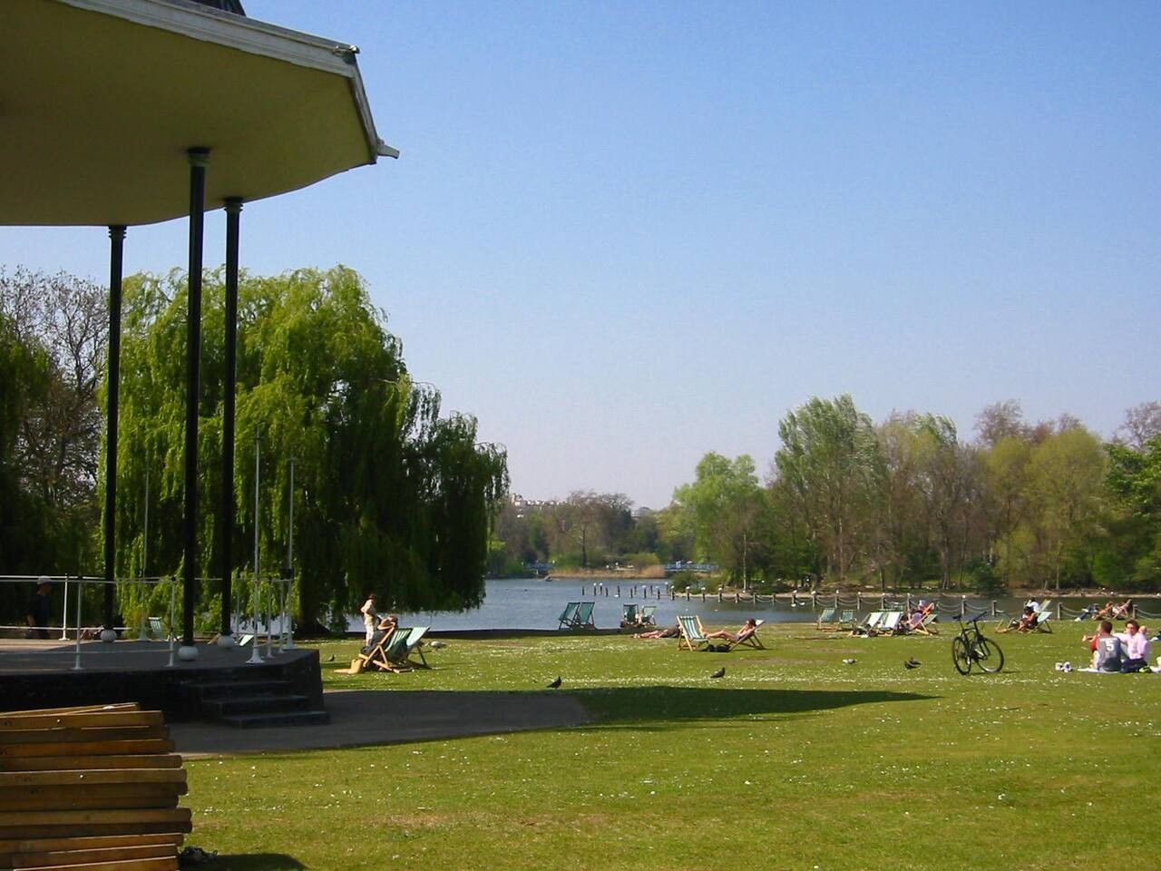 A park with a stage, seating areas, and a lake.