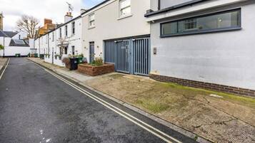 A residential street with houses, a gated driveway, and a paved road.