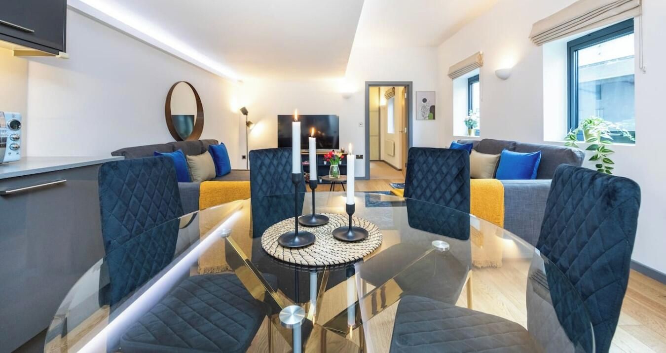Ein modernes Wohnzimmer mit einem Glastisch, zwei Sofas und einem Fernseher.