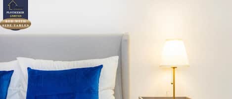 A bed with side tables, a lamp, and two candles on a nightstand.