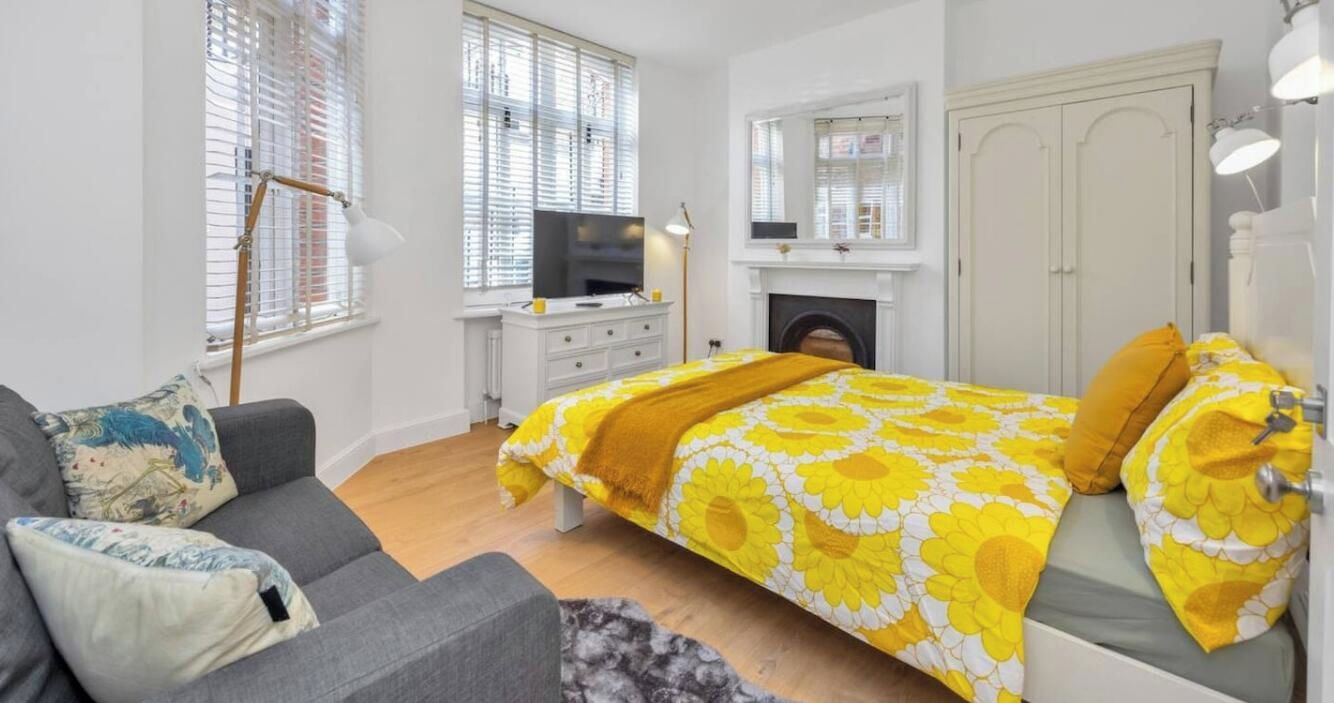 Um quarto com cama, sofá, televisão, lareira e guarda-roupa.