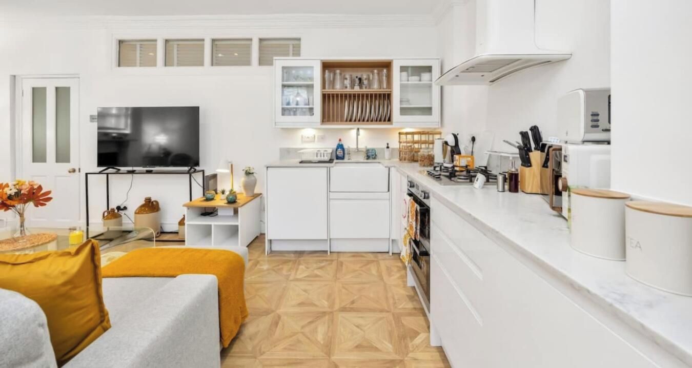 Una cocina moderna con armarios blancos, horno empotrado y una encimera con utensilios de cocina.