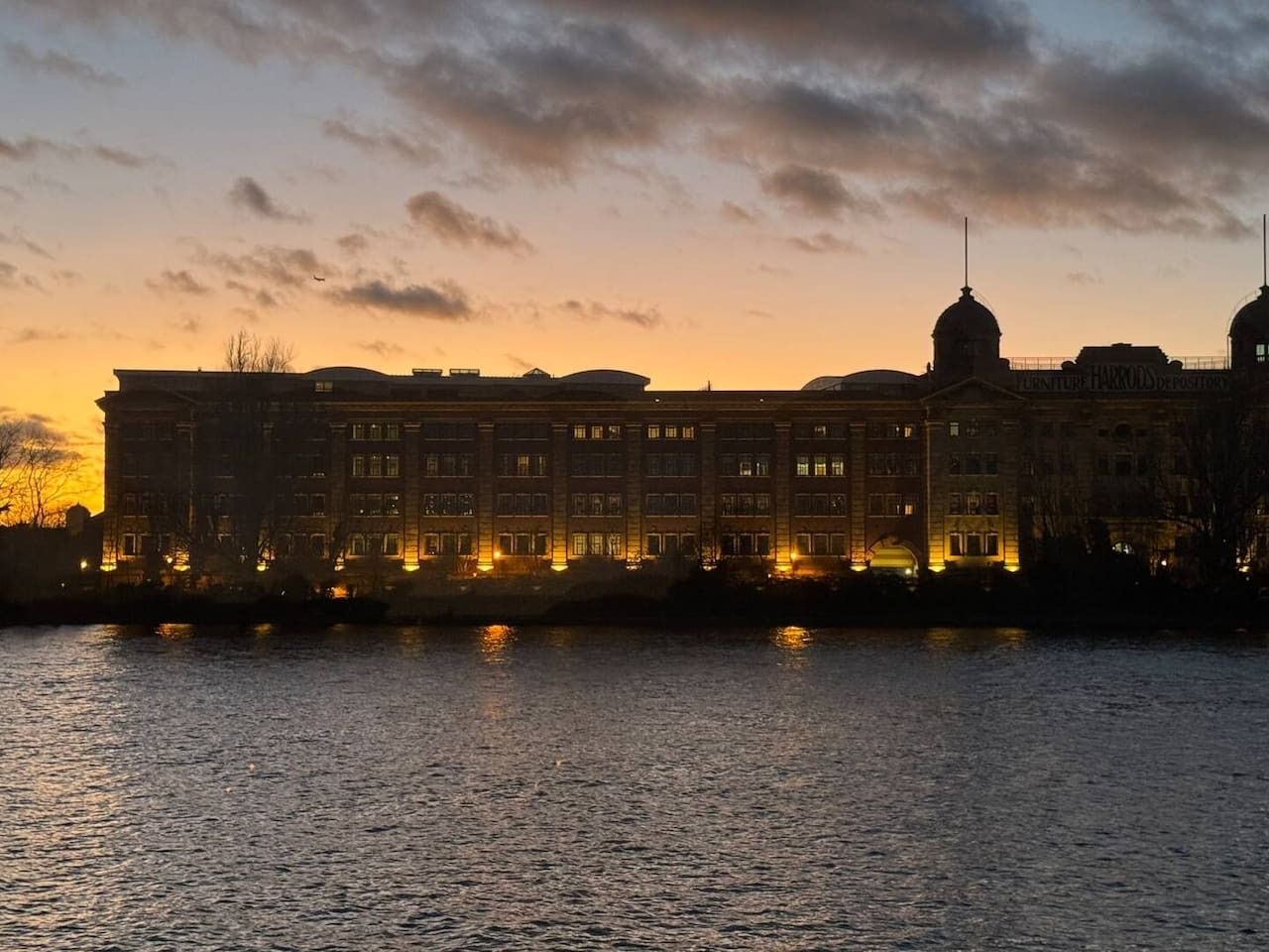 A large building with multiple floors and a prominent dome, situated by a body of water.
