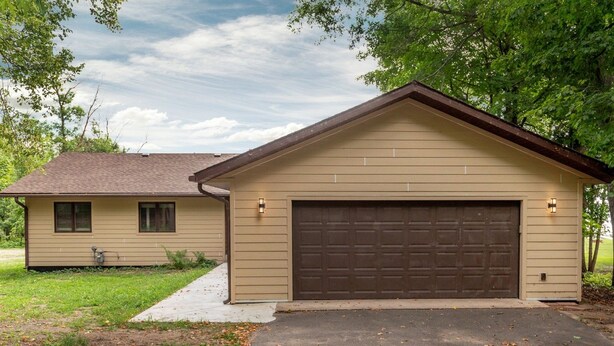 Una casa a un piano con garage, un piccolo deposito annesso e vialetto lastricato.