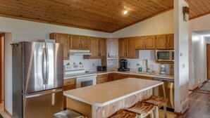 Una cucina moderna con elettrodomestici in acciaio inossidabile, pensili in legno e un'isola centrale con sgabelli da bar.