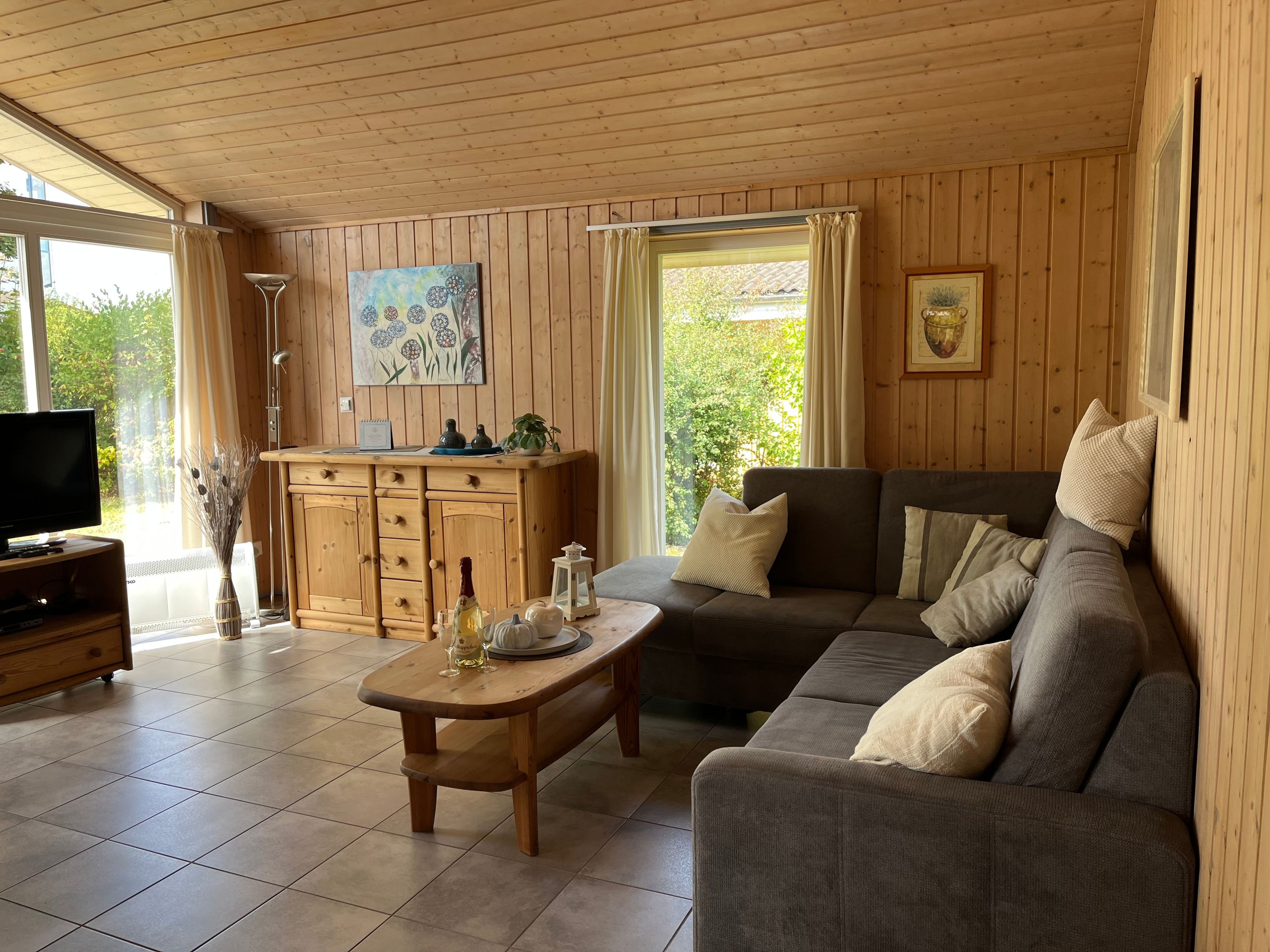 Ein gemütliches Wohnzimmer mit Holzbalkendecke, einer Couch, einem Couchtisch und einem Fernseher.