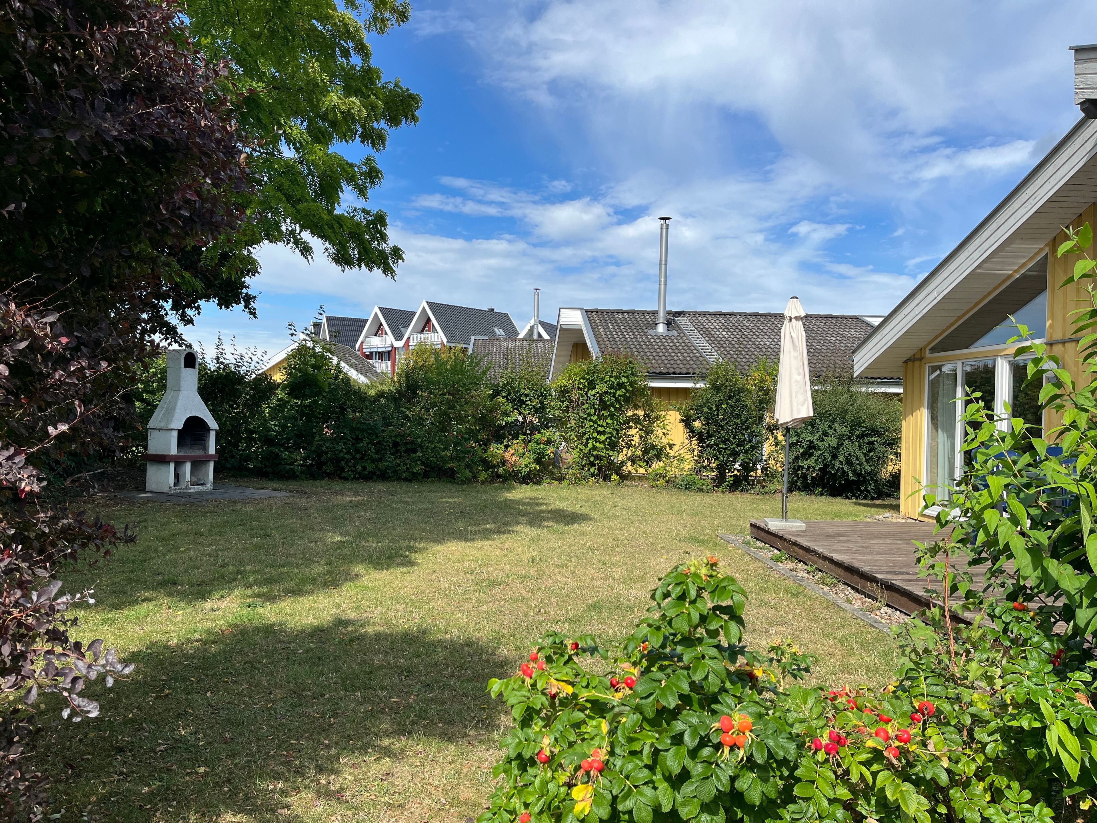 Ett bostadsområde med en gräsyta, en skorsten och ett hus med ett tak täckt av tegelpannor.