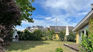 Ett bostadsområde med en gräsyta, en skorsten och ett hus med ett tak täckt av tegelpannor.