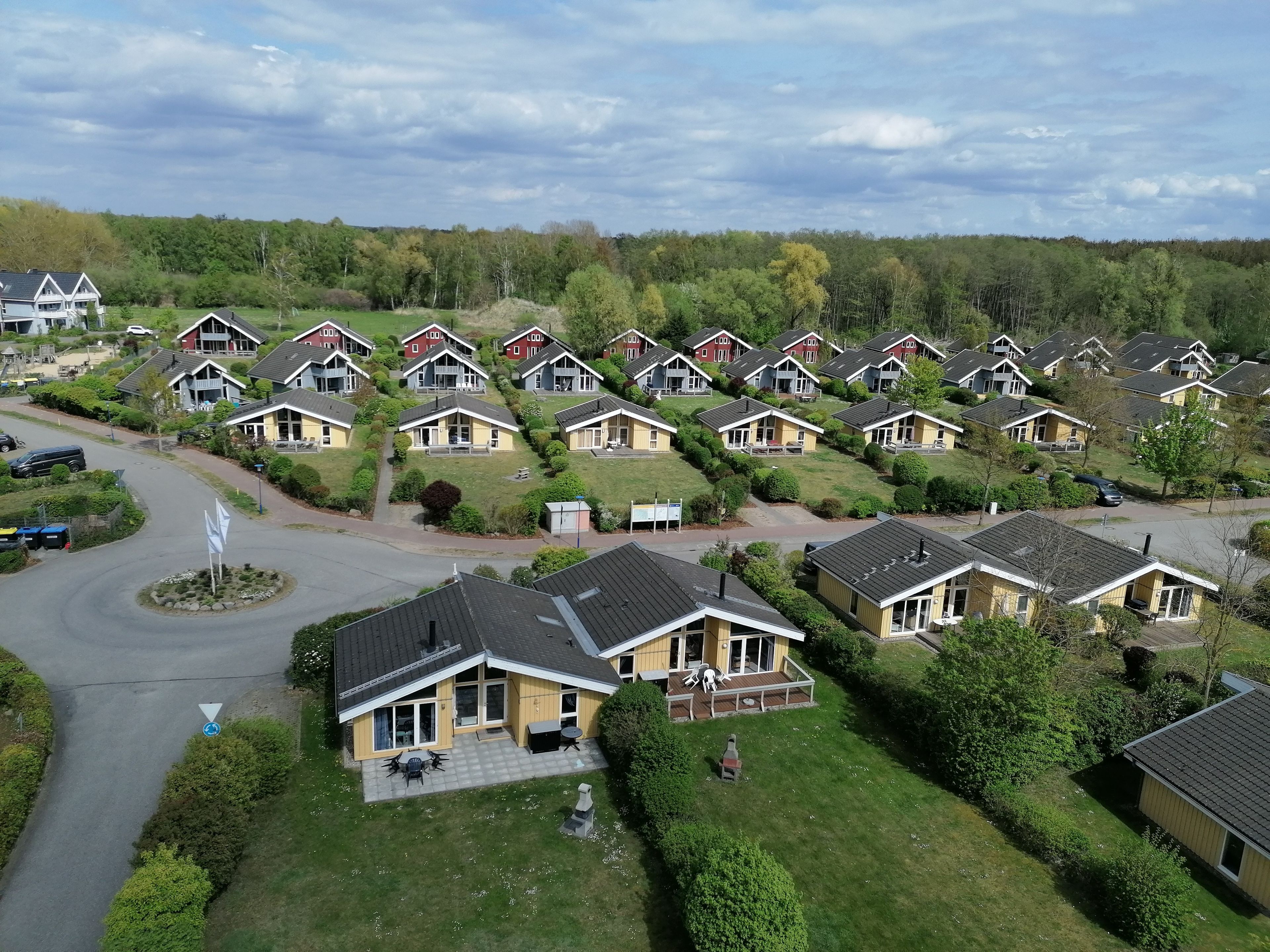 Un quartier résidentiel comprenant plusieurs maisons, un rond-point et un espace vert où flotte un drapeau.