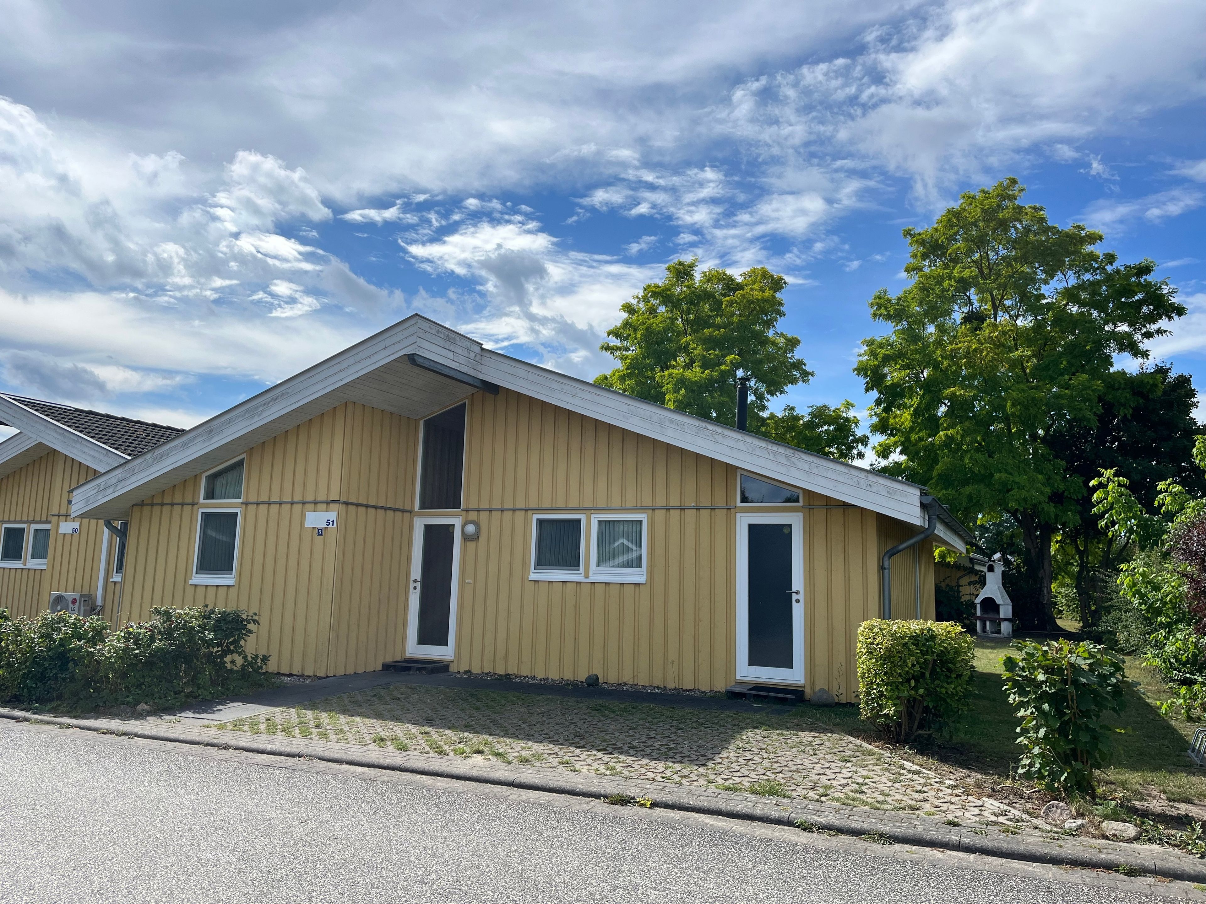 En tvåvåningsbyggnad med ett sadeltak, numrerad 51, med en ytterdörr, fönster och en liten veranda.