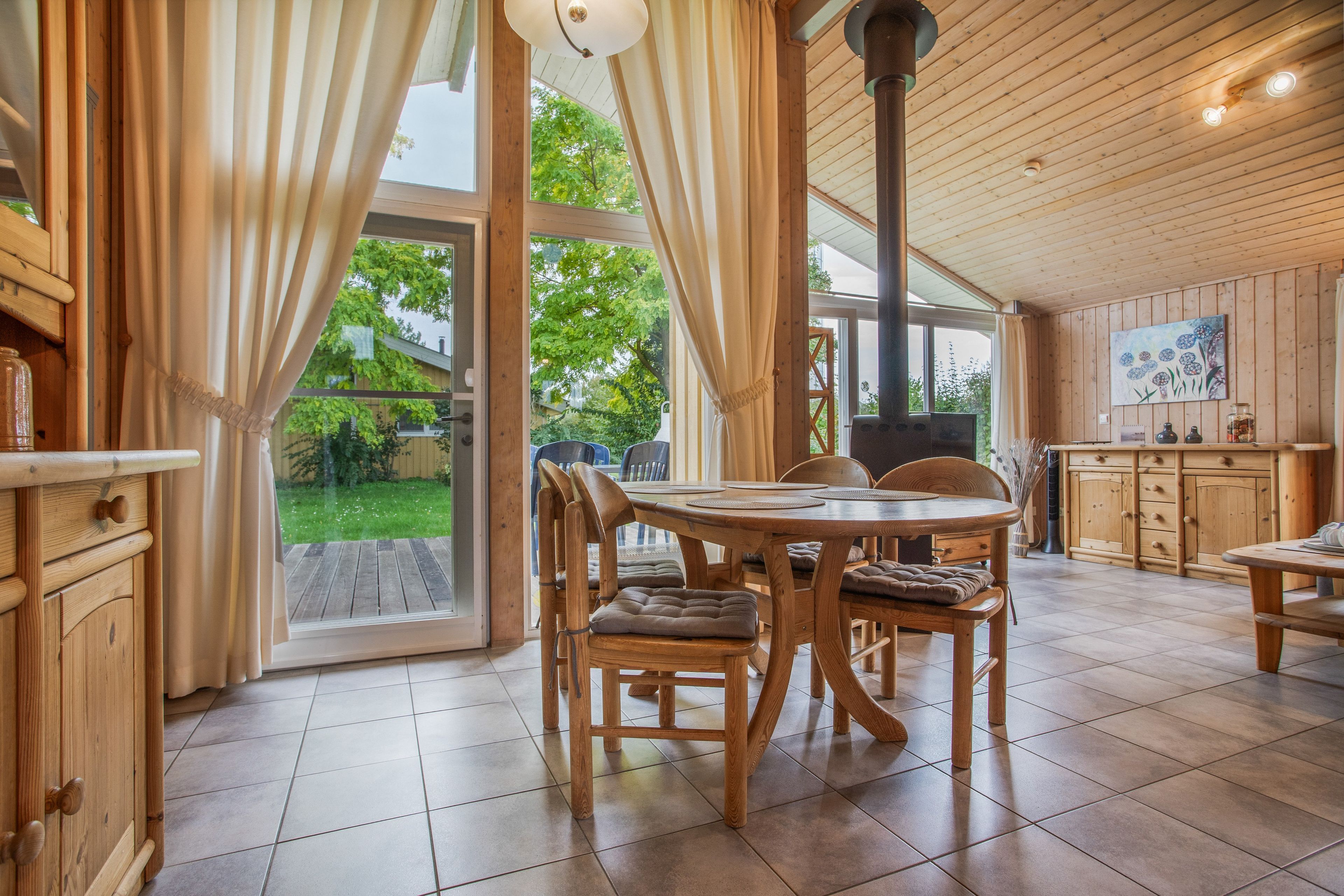 Un interior de madera con una mesa de comedor, sillas y una zona de cocina.