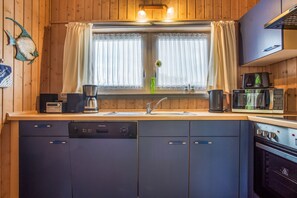 A kitchen with wooden cabinets, a dishwasher, a coffee maker, a microwave, and a stove. - Favorite Place – the "151-Step House"! (Rechlin)
