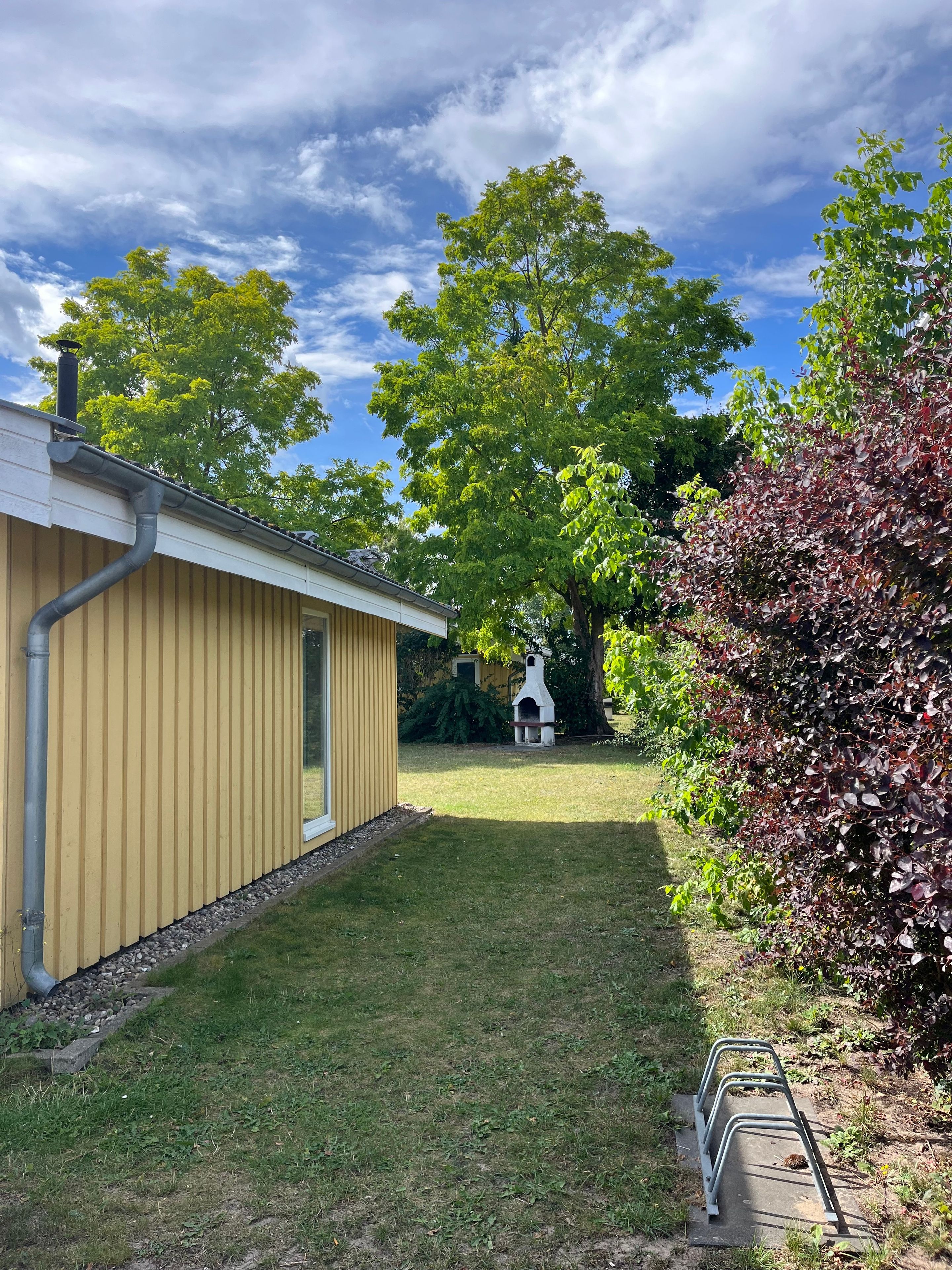 Une maison d’habitation à l’extérieur jaune, avec une pelouse et une cheminée blanche.