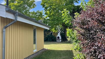 Une maison d’habitation à l’extérieur jaune, avec une pelouse et une cheminée blanche.