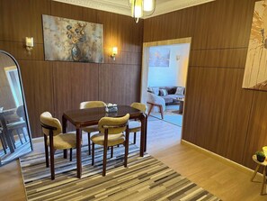 Un comedor con una mesa y sillas de madera, un tapete y un cuadro en la pared.