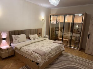 A bedroom with a bed, bedside tables, a wardrobe, and a chandelier. - 2BR Apartment in downtown Zamalek (Cairo Governorate)