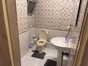Un baño pequeño con inodoro, lavamanos y una ventana sobre el inodoro.