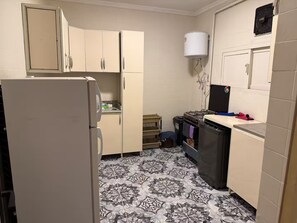 Eine kleine Küche mit Kühlschrank, Herd und Schränken.
