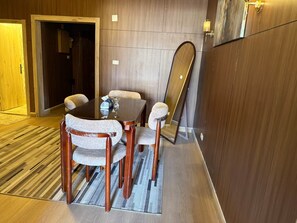 Ein Hotelzimmer mit Essbereich, ausgestattet mit einem Holztisch und Stühlen, einem großen Spiegel und einem Teppichboden.