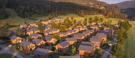 Zona residencial con varias casas de madera, calles y un paisaje montañoso al fondo.
