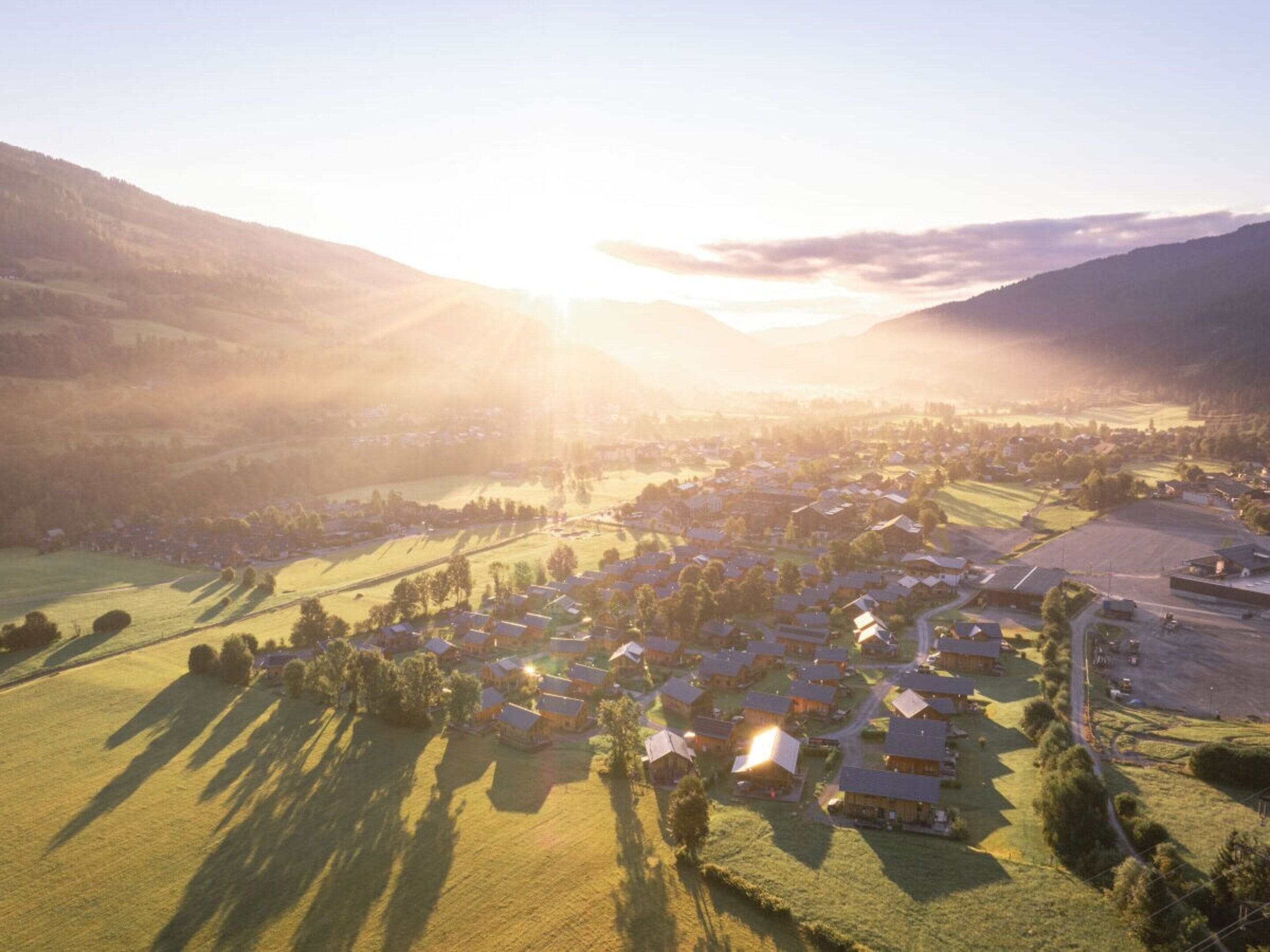 Un village rural où les maisons sont dispersées dans le paysage, entouré de champs et de collines.
