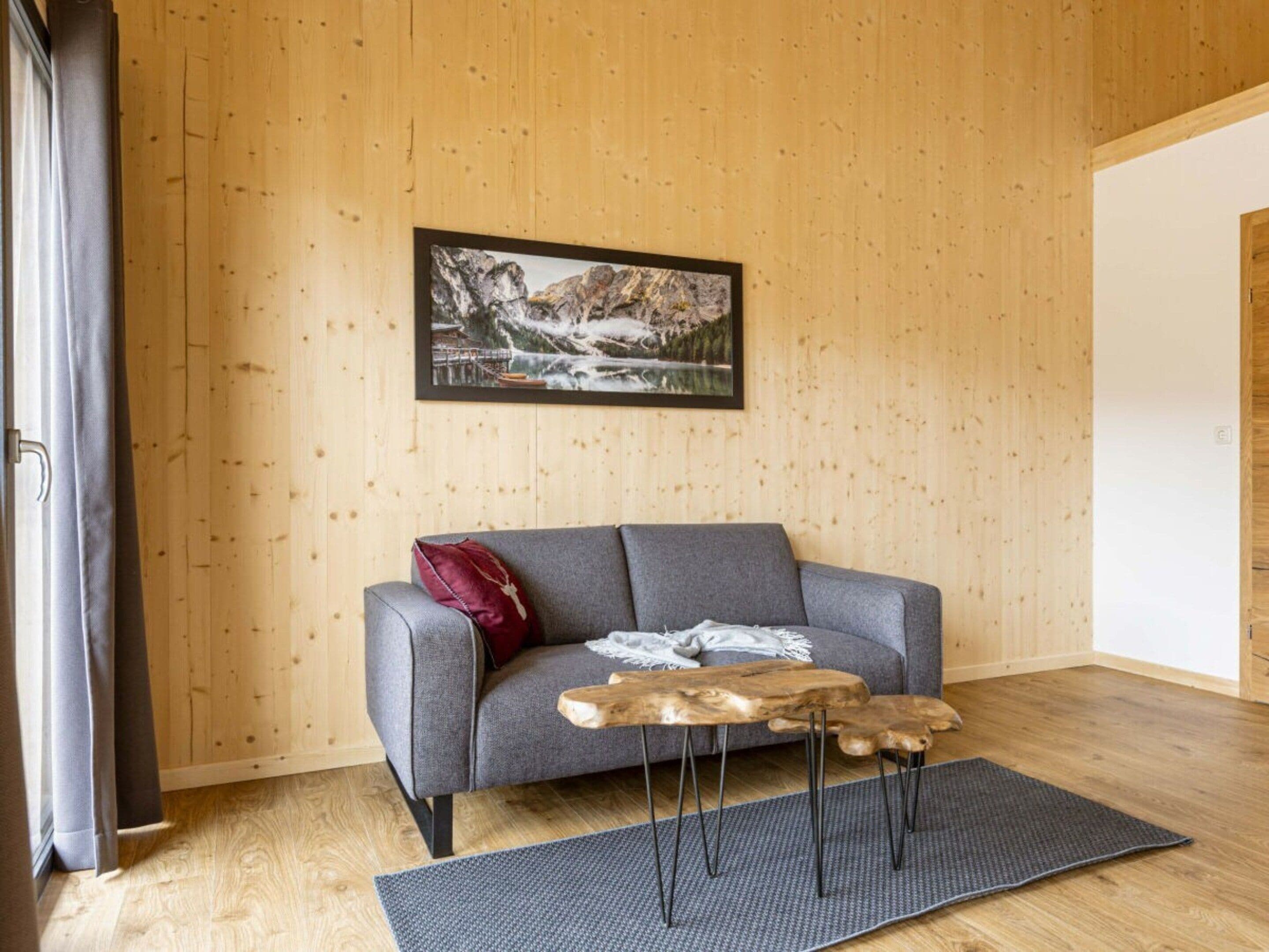 A modern living room with a grey sofa, a wooden coffee table, and a framed picture on the wall.