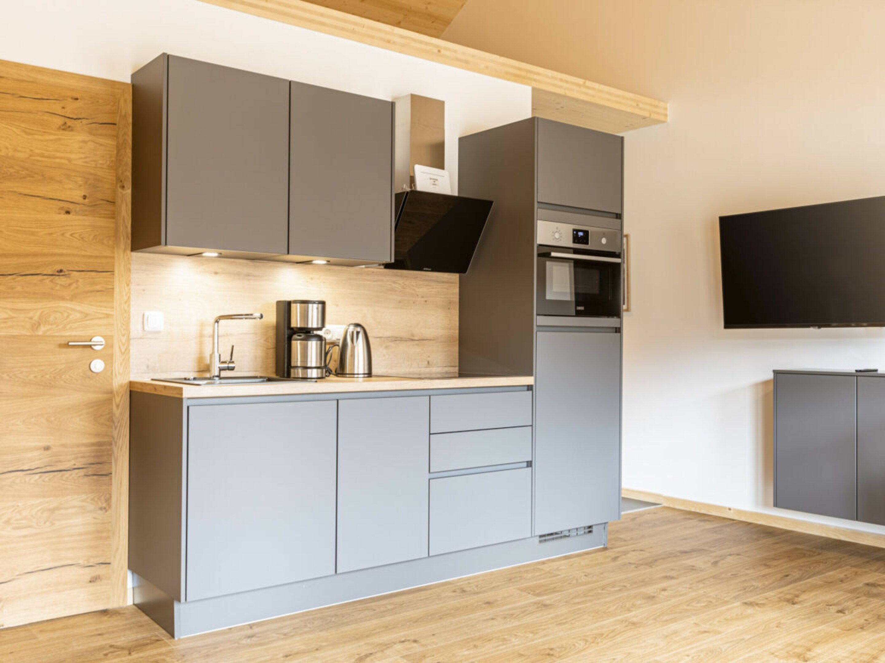 A modern kitchen with grey cabinets, a coffee maker, and an oven.