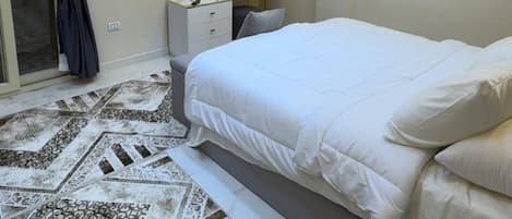Une chambre à coucher moderne avec un lit, une table de chevet et un téléviseur fixé au mur.