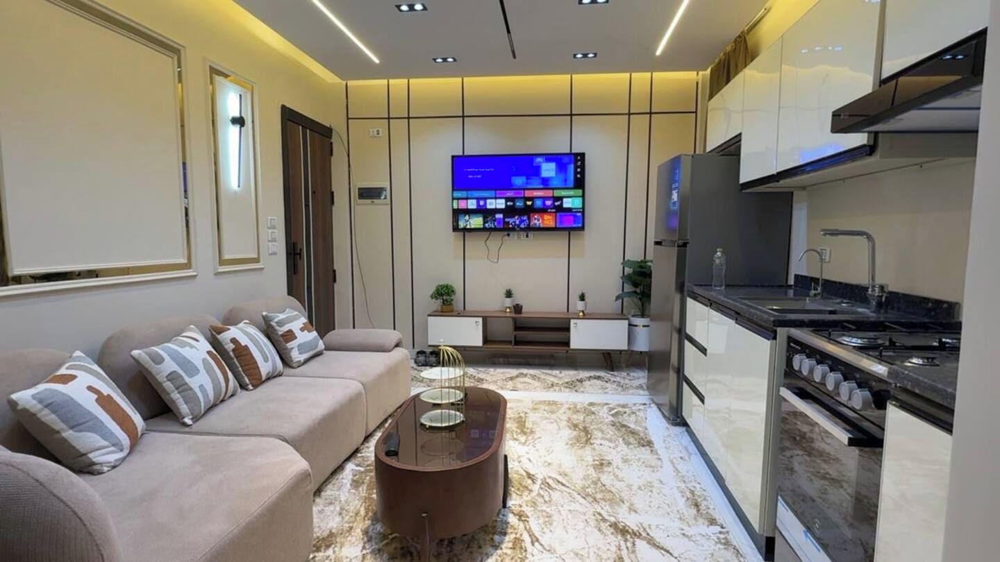 A modern kitchen with a built-in oven and a flat-screen TV mounted on the wall.