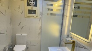 Un baño moderno con inodoro, lavamanos y ducha.